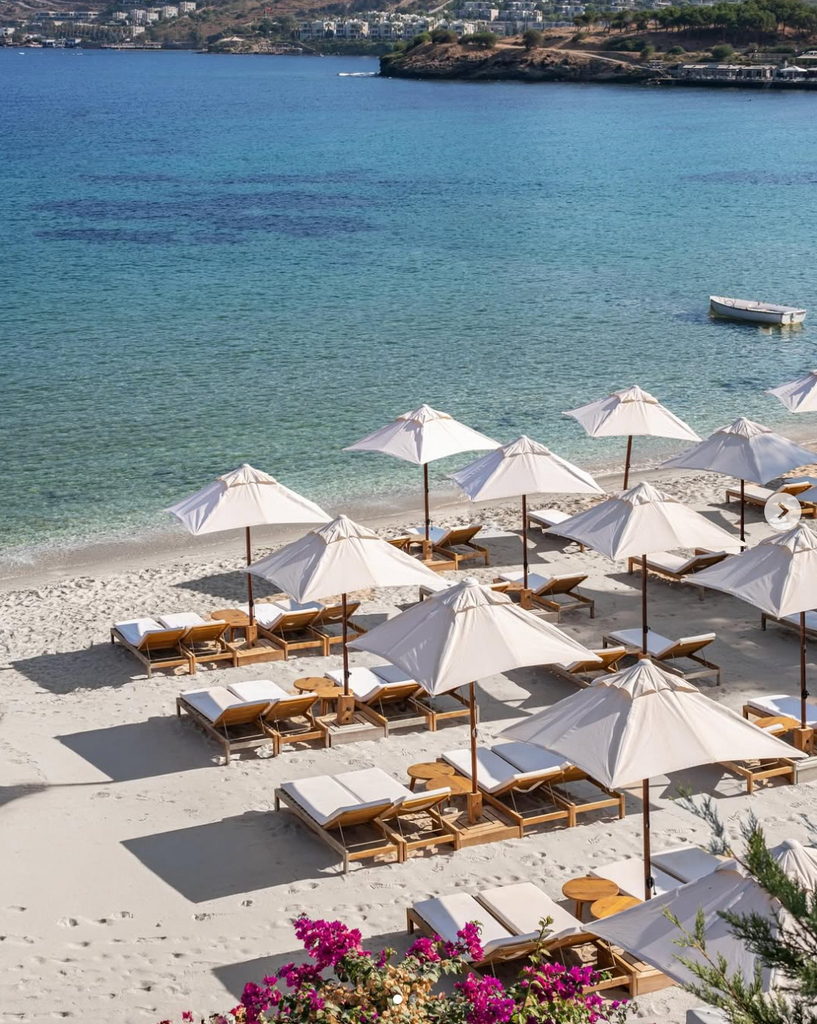 Beach with white umbrellas and lounge chairs near a body of water.